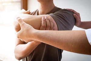 Chiropractor assisting patient with arm rehabilitation exercise